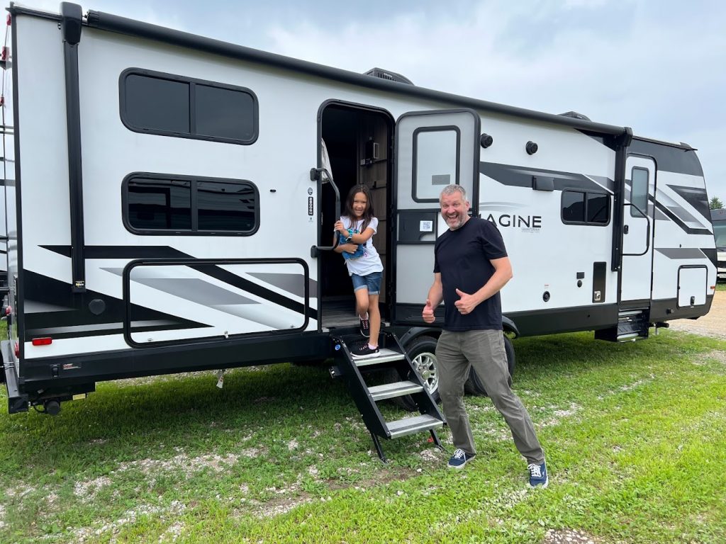Father and Daugther smiling outside a travel trailer