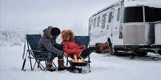 couple camping in snow outside camper