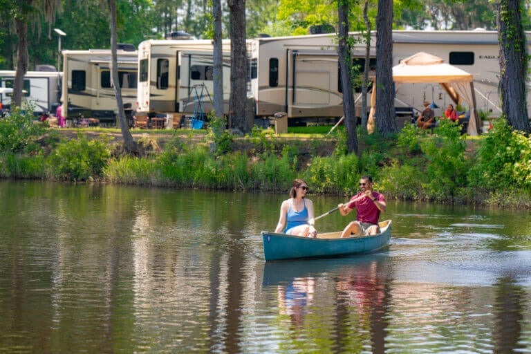 couple in a canoe on lake with RVs in background