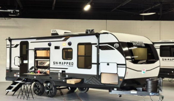 Forest River R-Pod Unmapped travel trailer displayed indoors with slide-outs extended and exterior kitchen open, featuring a modern white and black design.