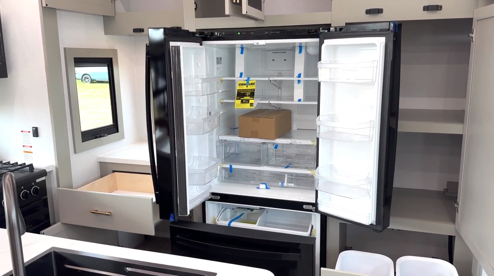 Residential-style French door refrigerator with freezer drawer inside the Axiom Imperium 12900 RV kitchen, surrounded by spacious cabinetry and modern storage solutions.