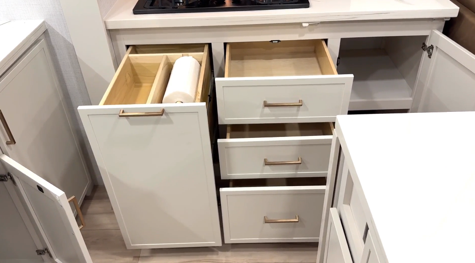 Detailed view of the Brinkley Model I 280 kitchen storage showing dovetail drawers, a tall pull-out cabinet with an integrated paper towel holder and trash storage, and additional lower cabinet space beneath the cooktop. The layout highlights Brinkley’s practical organization and high-end residential craftsmanship.
