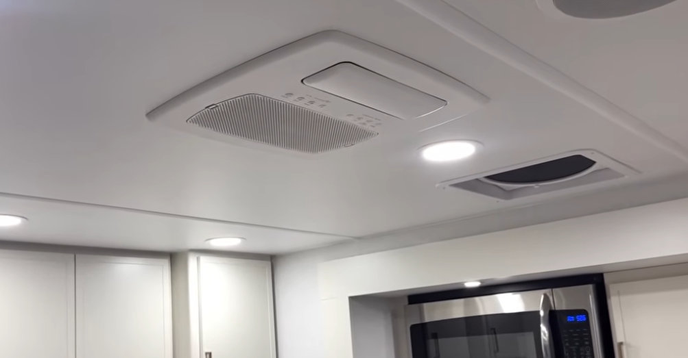 Ceiling view inside the Brinkley Model I 280 showcasing the ducted Furrion Chill Cube air conditioning system, LED recessed lighting, and a MaxxAir rain-sensing vent fan above the kitchen area. The setup highlights the RV’s efficient, quiet climate control and modern, residential-style interior design.