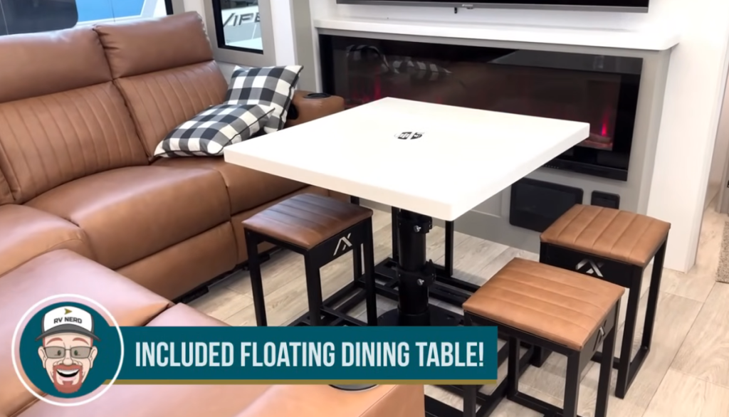 Modern RV living area in the 2026 Axiom Imperium I3800 featuring a floating dining table with four cushioned stools, brown leather sectional, black-and-white plaid pillow, and built-in electric fireplace beneath a mounted TV.