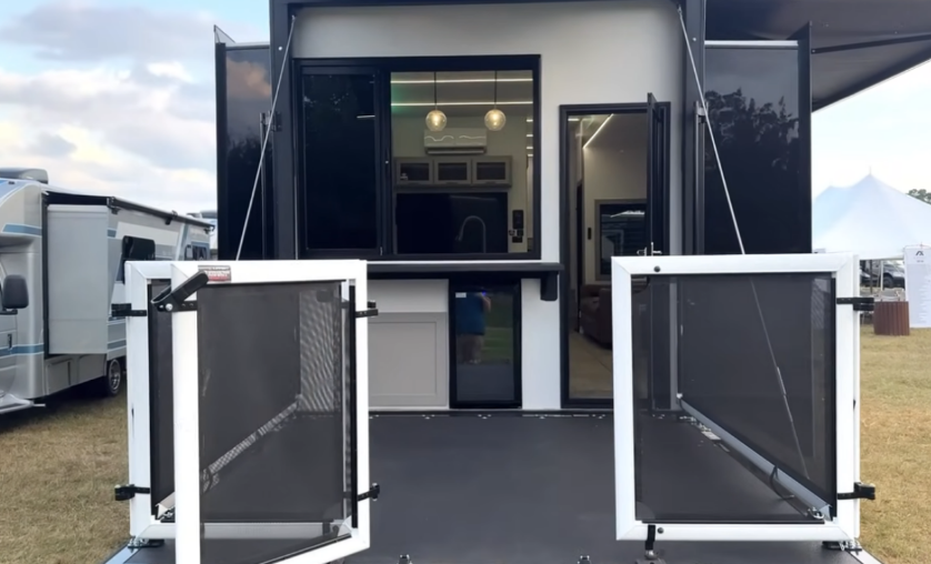 Rear view of the 2026 Axiom Imperium I3800 fifth wheel showcasing the elevated patio deck with fold-down railings, outdoor bar setup with mini fridge, and view into the modern interior kitchen and living area.