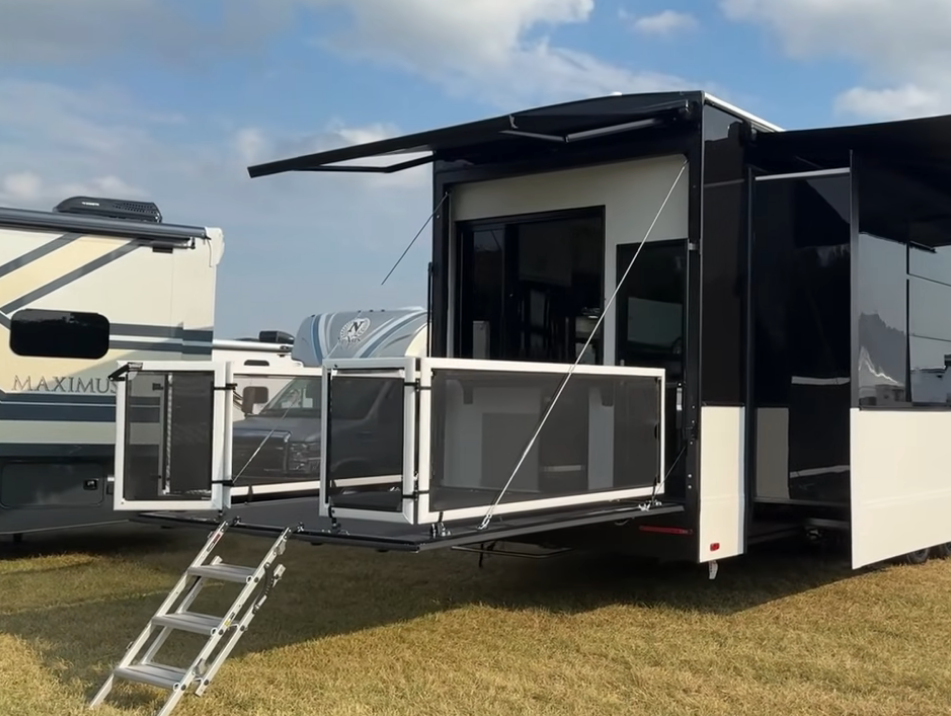 Rear patio deck of the 2026 Axiom Imperium I3800 fifth wheel extended with safety railings and fold-down stairs, showcasing the luxury RV’s outdoor entertainment space and modern black-and-white exterior design.