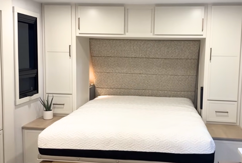 Brinkley Model Ix 20X bedroom with Murphy bed lowered, padded headboard, modern cabinetry, side wardrobes, and soft neutral lighting for a luxury residential feel inside the travel trailer.