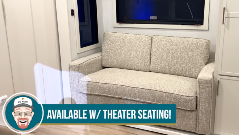 Brinkley Model Ix 20X optional theater seating setup with light fabric two-seat sofa in front of large window, highlighting the customizable living area in the luxury travel trailer.