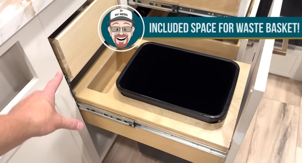 Brinkley Model Ix 20X kitchen drawer with built-in wastebasket storage and organizer slots, showing the smart cabinetry design inside the compact luxury travel trailer.