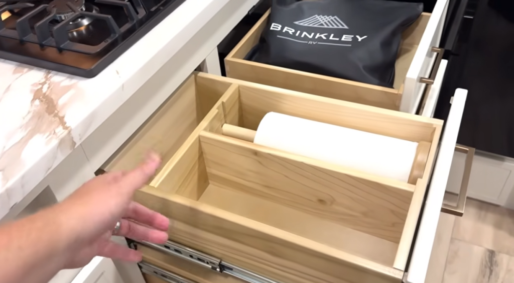 Brinkley Model Ix 20X kitchen drawer system featuring built-in paper towel holder and organized storage compartments beneath marble-look countertops for convenient RV living.