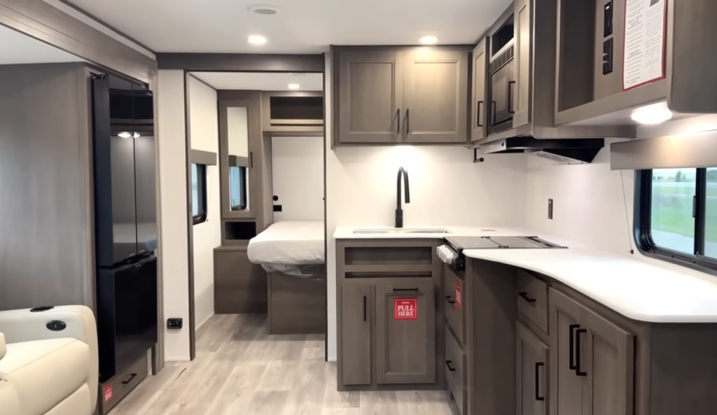 Grand Design Transcend Xplor 22RBX interior featuring L-shaped kitchen with modern cabinetry, residential-style faucet, and walk-around queen bed in the rear bedroom.