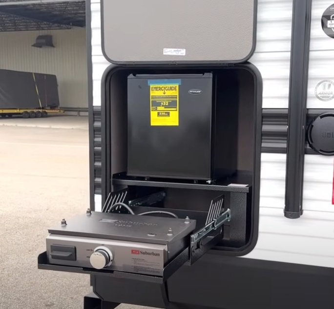 Grand Design Transcend Xplor 22RBX exterior kitchen with slide-out Suburban griddle and compact mini fridge, designed for convenient outdoor cooking and storage.