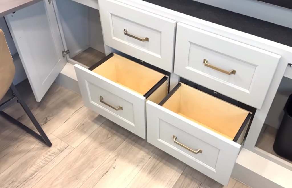 Brinkley Model G Series luxury RV interior showing dual deep storage drawers with gold handles under a solid-surface countertop and soft-close cabinetry, highlighting upscale residential design and organization space.