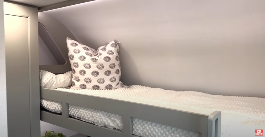 Brinkley Model G Series RV bunk bed with soft white bedding, decorative pillows, and integrated LED accent lighting, designed for comfort and modern family-friendly sleeping space.