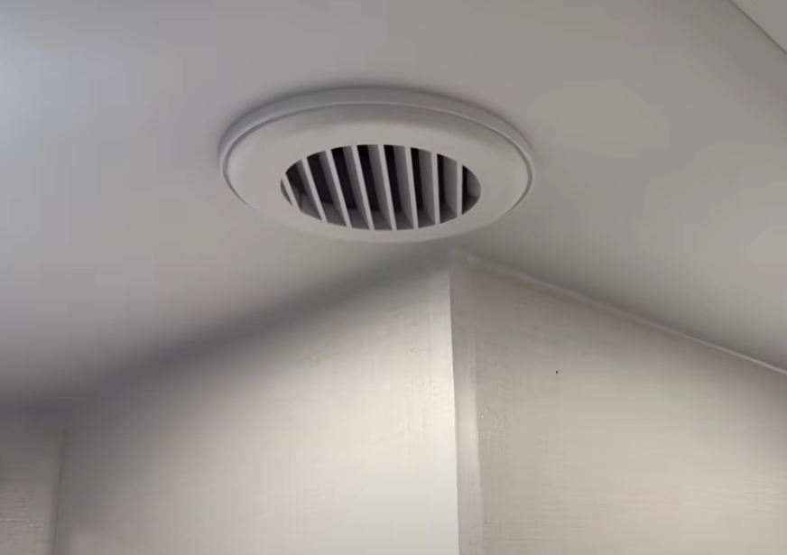Brinkley Model G Series RV ceiling vent close-up showing the ducted air conditioning system with residential-style circular grille, designed for quiet, even climate control throughout the coach.