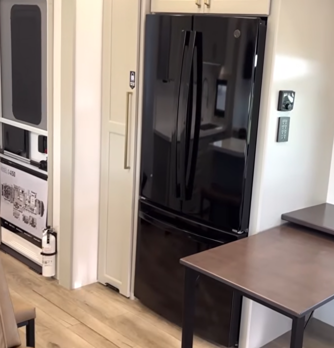 Brinkley Model G Series RV kitchen featuring a sleek black residential French-door refrigerator with bottom freezer, modern cabinetry, and adjacent workspace for a seamless, home-style design.