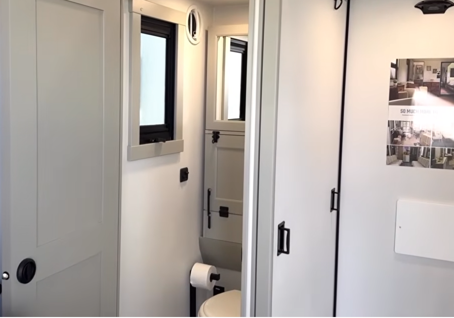Brinkley Model G Series RV garage half bath featuring a compact vanity with mirrored cabinet, modern fixtures, window ventilation, and sliding privacy door for convenient guest use.