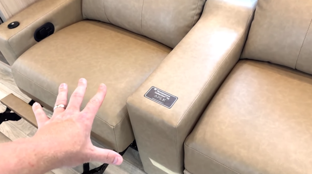 Close-up of the 2026 Winnebago Thrive 22MLS theater seating with tan leather recliners, powered footrests, and X30 Apex Comfort foam cushions for enhanced relaxation and durability.