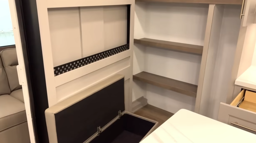 Alliance Paradigm fifth wheel kitchen pantry with open shelving and hidden storage bench, offering additional organization space next to the main living area.