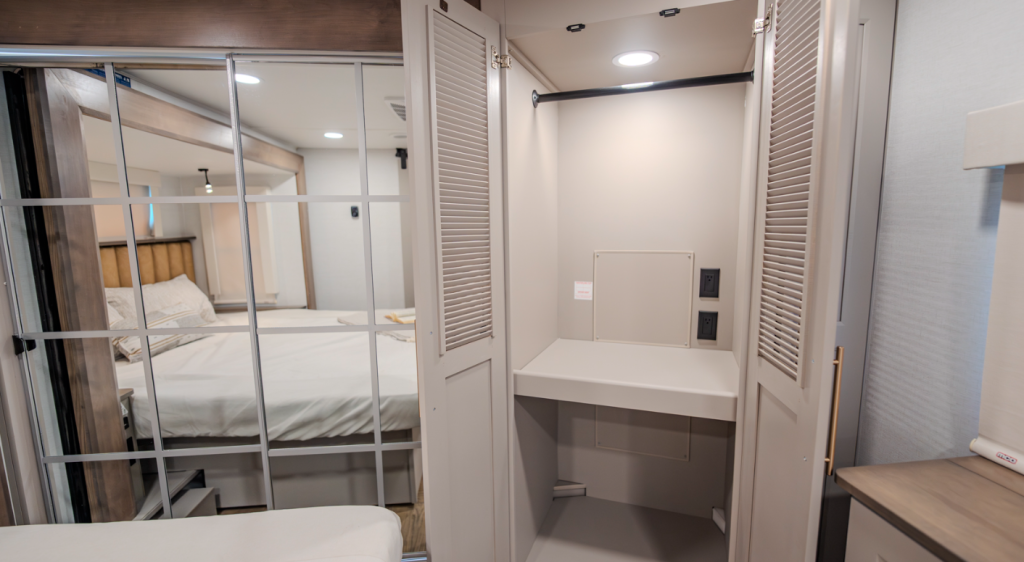Alliance Paradigm fifth wheel mirrored wardrobe with washer and dryer prep area, built-in outlets, and spacious hanging storage beside the king bed.