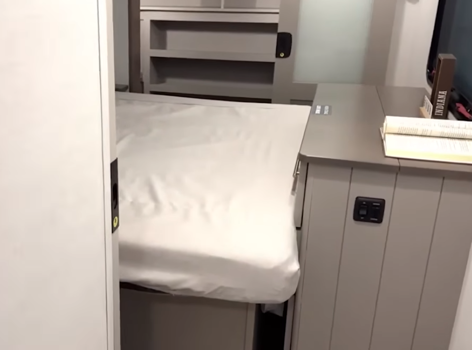 Alliance Paradigm bedroom access with slides closed, showing partial walkway around the bed and nightstand area with built-in power outlets.