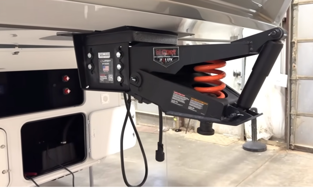 CURT Helux pin box hitch system on an Alliance Paradigm fifth wheel, showing upgraded suspension spring and shock absorber for smoother towing performance.