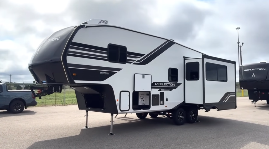 2026 Grand Design Reflection 150 Series 270BN fifth wheel with aerodynamic front cap, dual-axle design, and large slide-out, parked for display under cloudy skies.