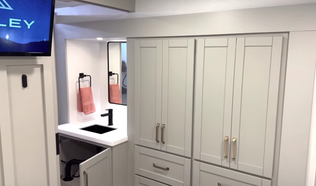 Brinkley Model Z bathroom and bedroom transition area showcasing modern cabinetry with gold hardware, a sleek black faucet vanity, and soft accent lighting for a residential, upscale look.