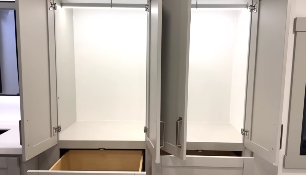 Brinkley Model Z bedroom storage cabinets open to reveal dual lighted wardrobes with hanging rods and deep lower drawers, offering ample space for clothing and travel essentials.