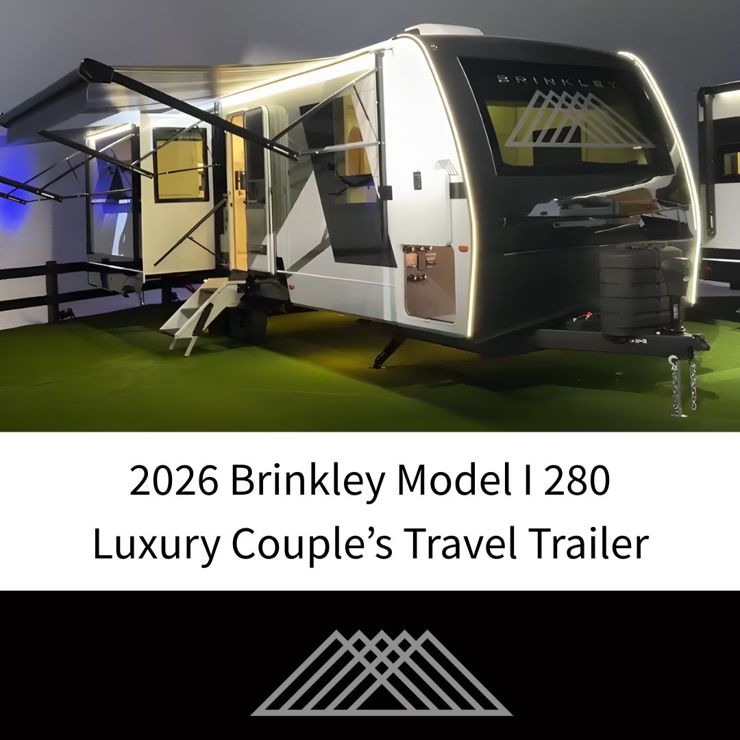 Promotional image of the 2026 Brinkley Model I 280 luxury couple’s travel trailer showcasing its modern exterior design with LED accent lighting, dual slide-outs, and illuminated Brinkley logo. The trailer sits under display lighting, highlighting its premium build and upscale appeal for travelers seeking comfort and style.