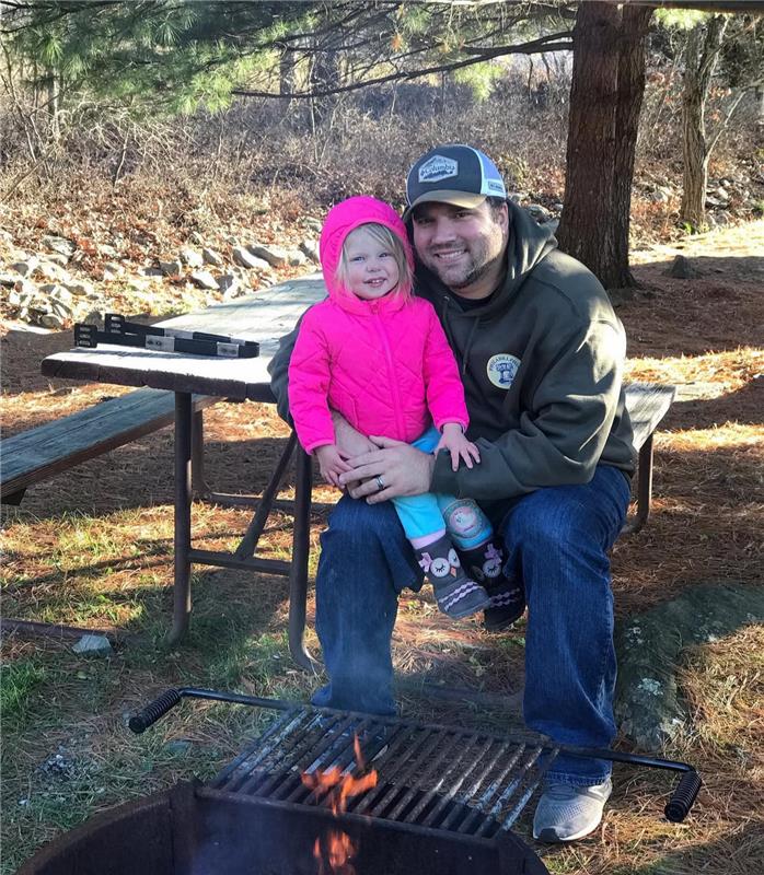 Family standing in front of the illuminated Bish’s RV logo wall inside the dealership, smiling together for a warm and welcoming customer photo.
