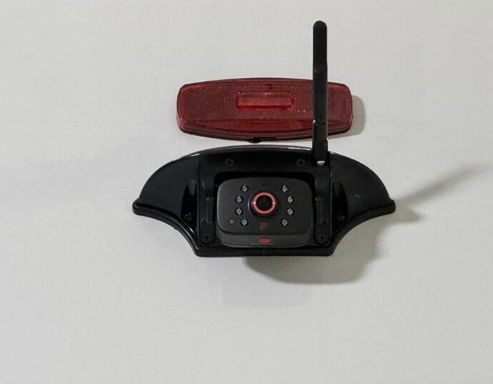 Close-up of an RV backup camera with night vision LEDs and antenna mounted below a red clearance light, designed for improved visibility and safety while reversing.