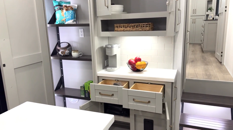 Brinkley Model Z 3600 kitchen coffee bar and pantry area featuring pull-out drawers, upper cabinets, a Keurig coffee maker, subway tile backsplash, and open shelving with organized storage.