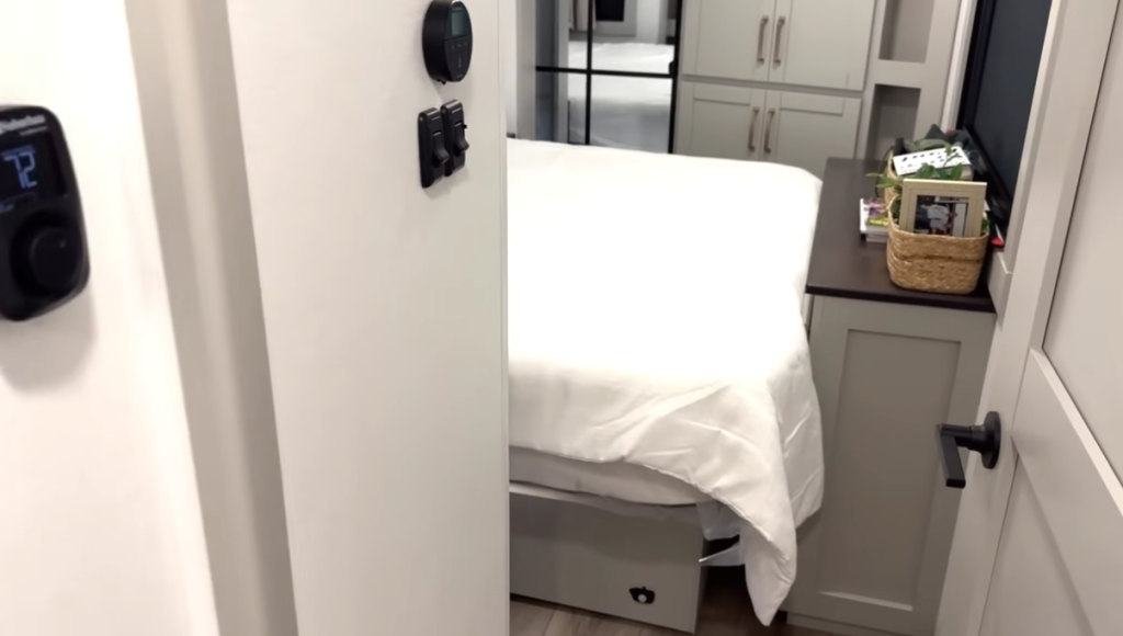 Bedroom inside the Brinkley Model Z 3600 fifth wheel featuring a neatly made bed, mirrored wardrobe storage, built-in dresser with countertop, and soft neutral interior design.