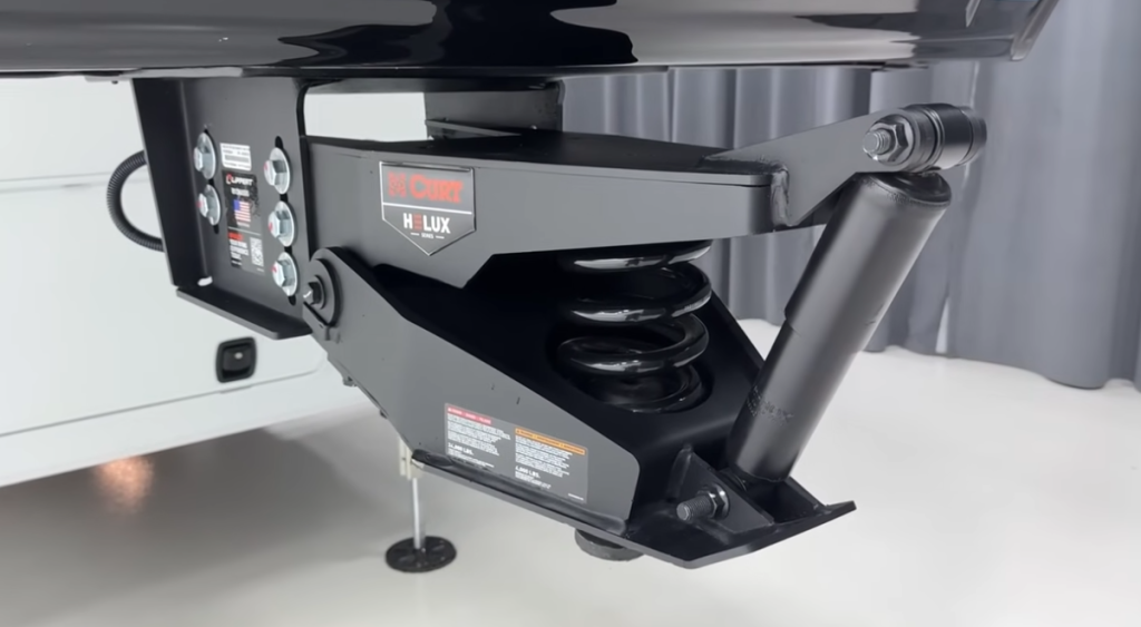 Close-up view of the CURT Helux pin box with integrated coil spring and shock absorber system on a Brinkley fifth wheel, designed to improve ride stability and towing comfort.