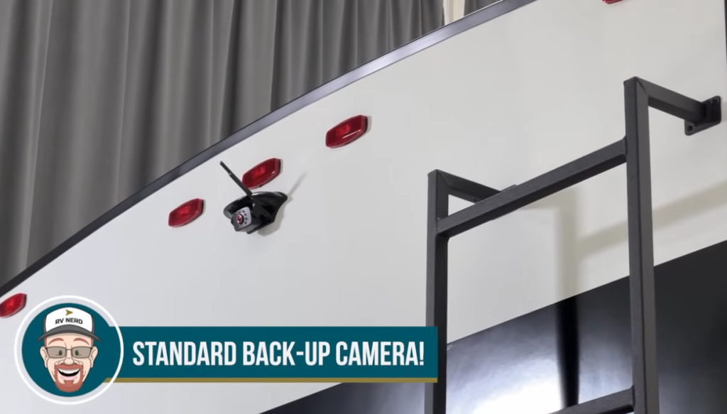 Rear view of a Brinkley RV showing the standard backup camera mounted above the ladder, with red clearance lights along the top for added safety and visibility.