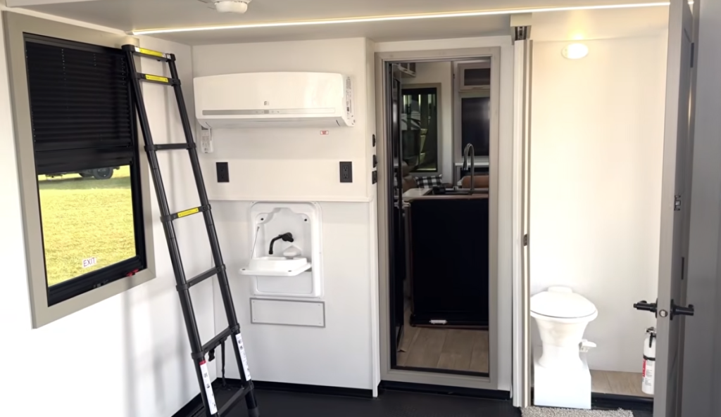 Garage and half bath area of the 2026 Axiom Vendetta 4250 fifth wheel featuring a mini-split climate system, loft ladder, washer/dryer hookups, and compact bathroom with modern fixtures.