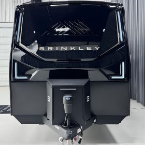 Front view of a sleek black Brinkley travel trailer showcasing its modern aerodynamic design, LED front lighting, and premium electric tongue jack inside a showroom setting.
