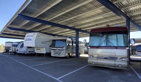 Covered RV storage facility with multiple motorhomes and fifth wheels parked in shaded spaces, showcasing secure off-season RV storage and protection from sun exposure.