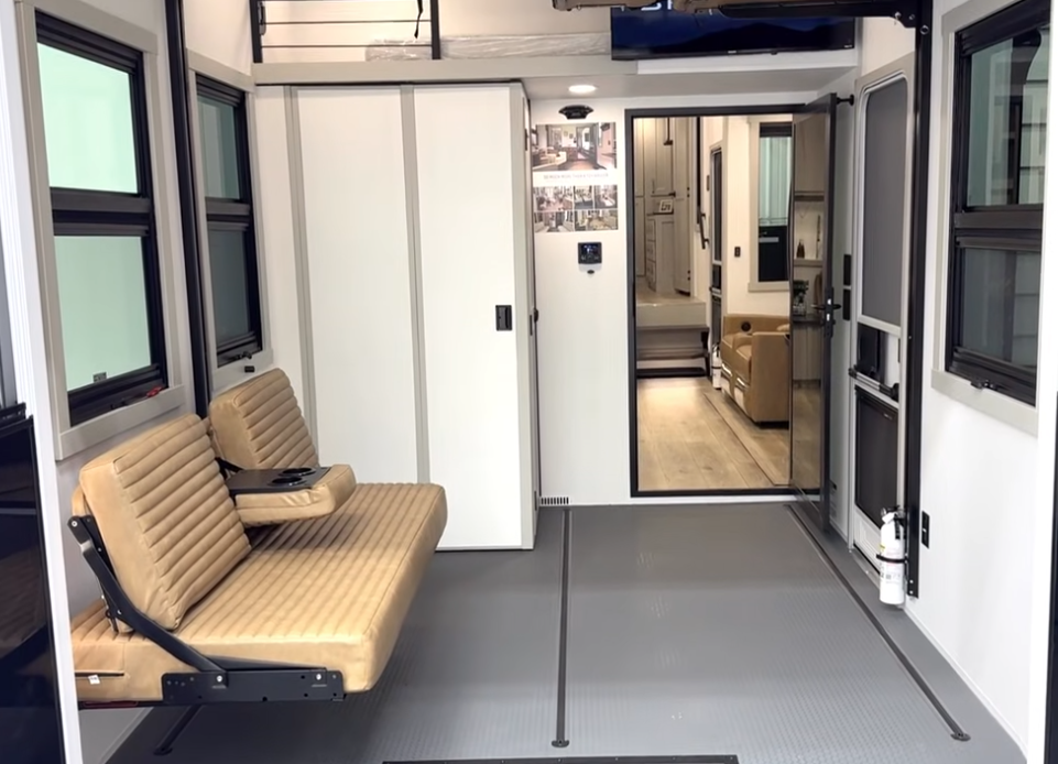Brinkley toy hauler garage with fold-down bench seating, large windows, durable rubberized flooring, and sliding door entry into the main living area.