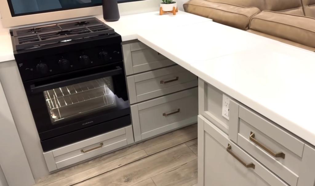 Brinkley Model Z 3200 RV kitchen with Furrion oven and cooktop, expanded solid-surface countertops, gray cabinetry, and spacious lower drawer storage.