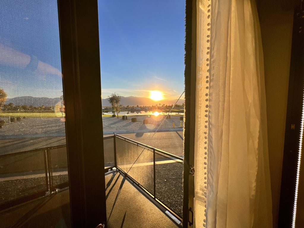 Beautiful sunset behind the mountains viewed through the patio doors of an RV toyhauler