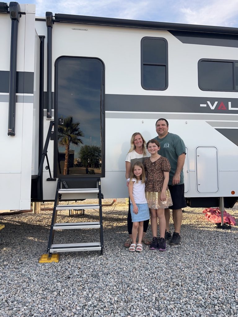 Family standing outside of their toyhauler Valor RV posing for a photo