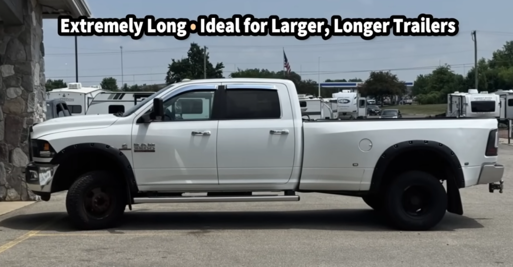 Long-wheelbase heavy-duty pickup truck parked at an RV dealership, illustrating extended length and improved stability for towing large, long travel trailers or fifth wheels.