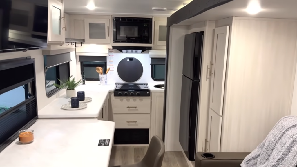 Travel trailer kitchen with refrigerator, microwave, stove, sink, and wraparound counter space