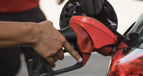 Person pumping gasoline into vehicle at fuel station