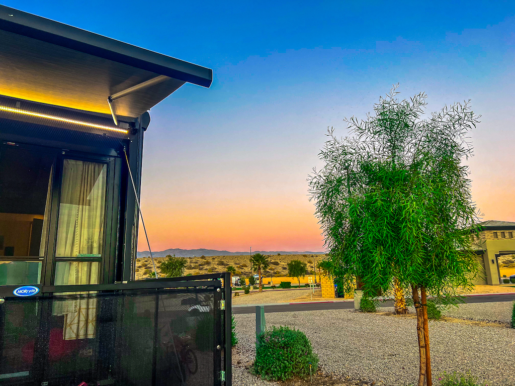 RV patio at a desert RV resort during sunset with outdoor lighting, landscaping, and mountain views