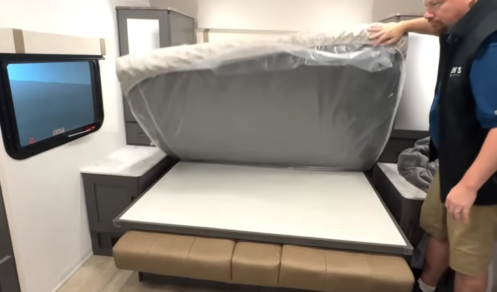 RV Murphy bed being folded down over sofa with mattress still wrapped in protective plastic