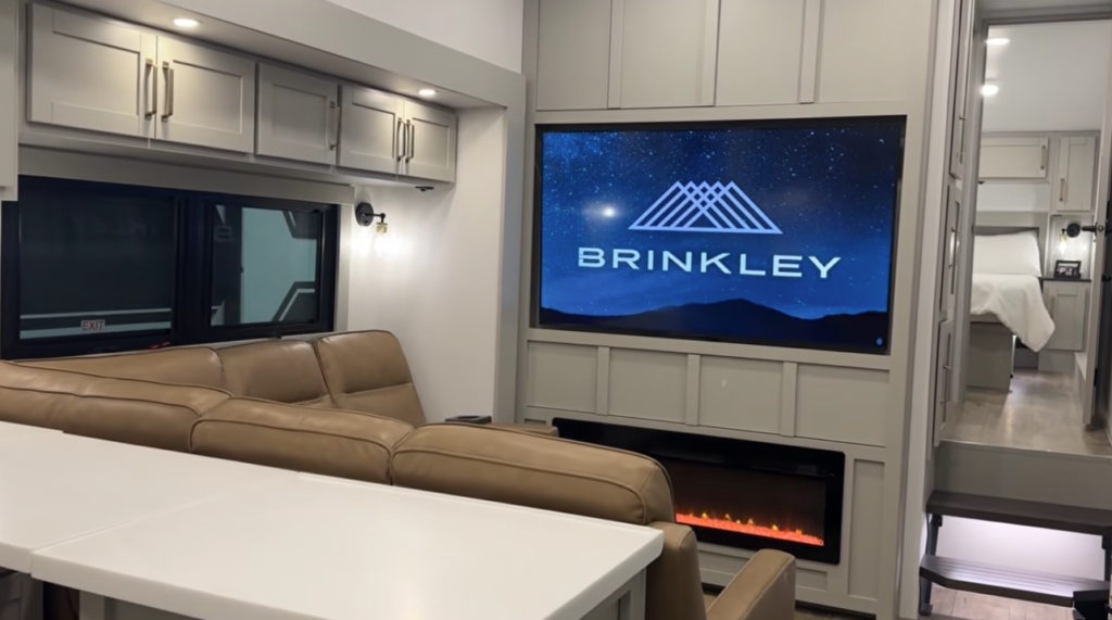 Brinkley RV living room with sofa, large TV, and electric fireplace
