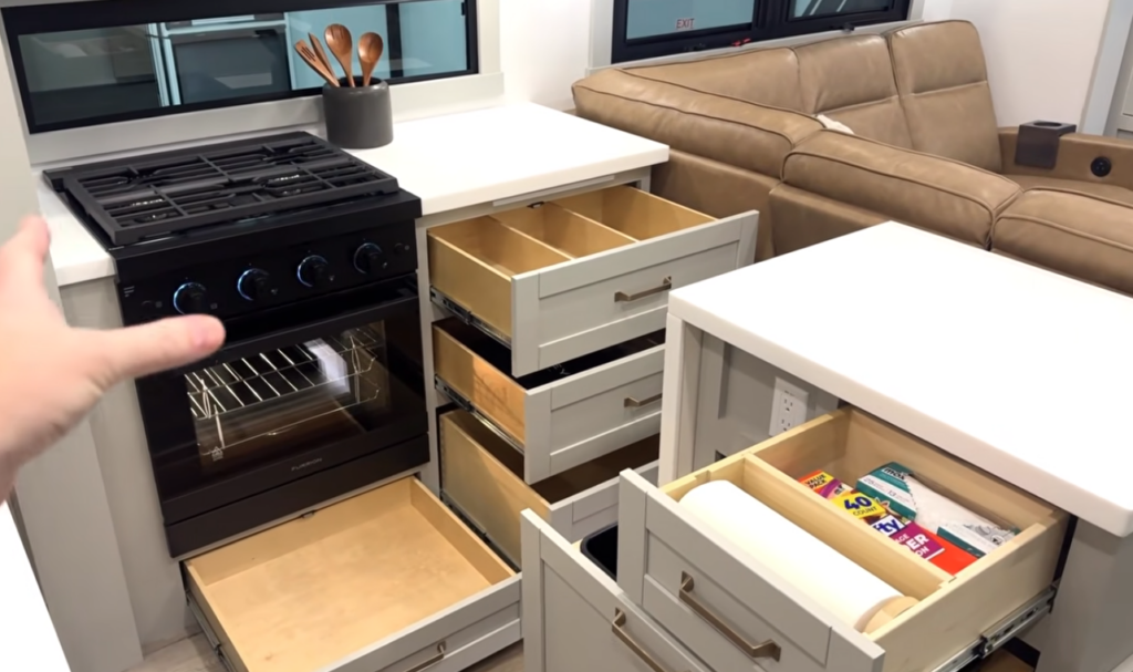 RV kitchen with open storage drawers and propane oven